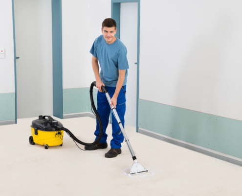 Male Cleaner Vacuuming Floor